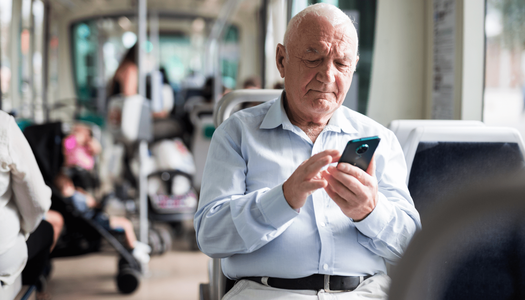 persona mayor utiliza un teléfono móvil mientras viaja en un autobús urbano.