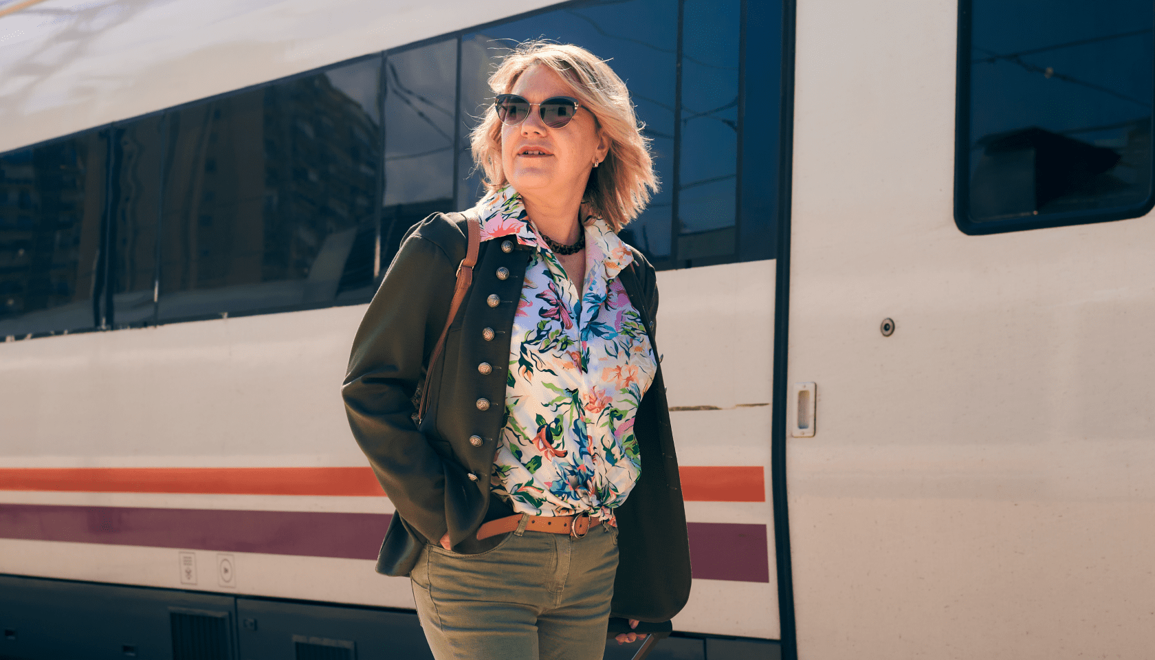 Mujer adulta paseando por delante de un tren Renfe en una estación de trenes.