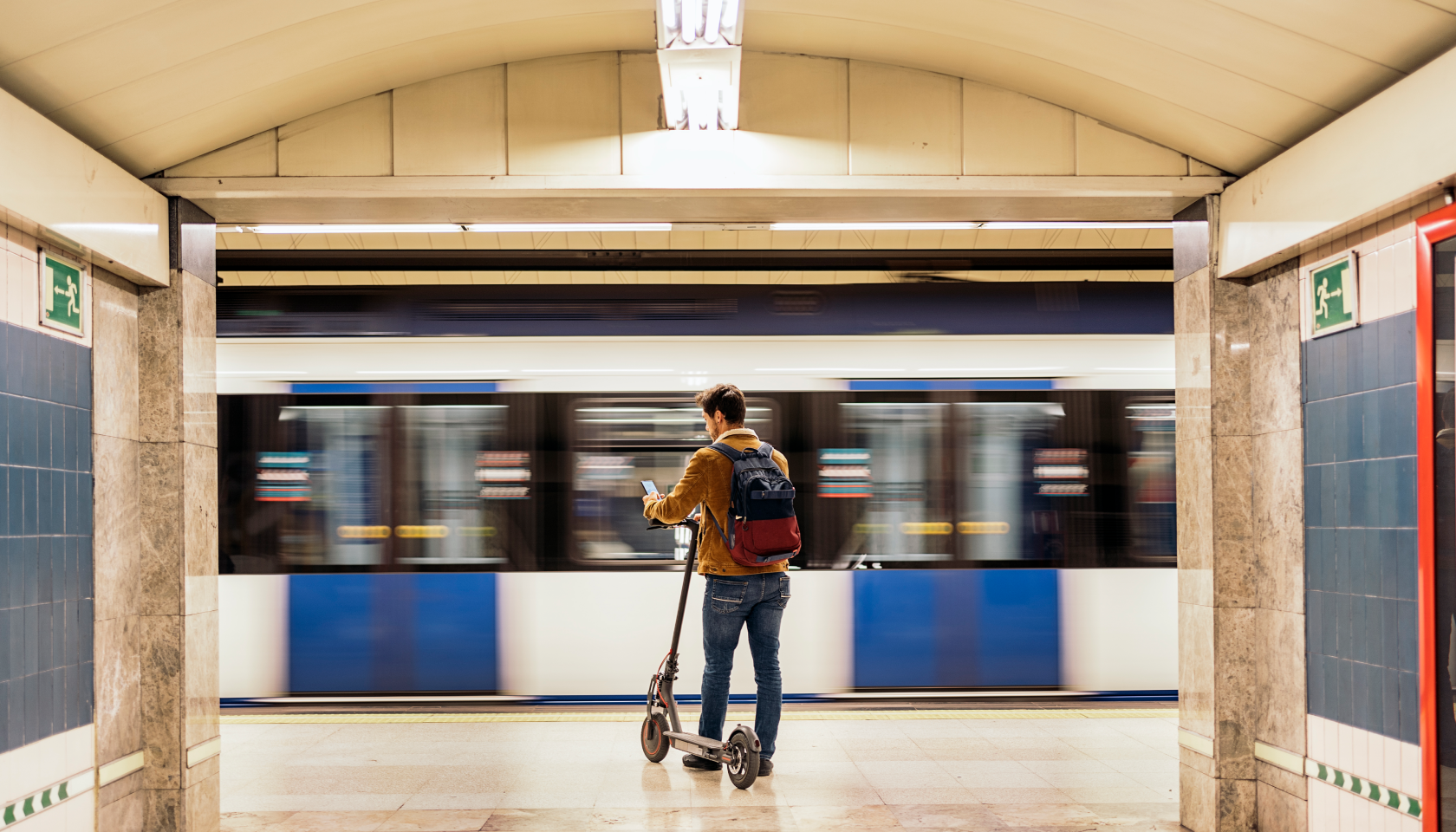 Imagen de un chico con un patinete esperando un tren