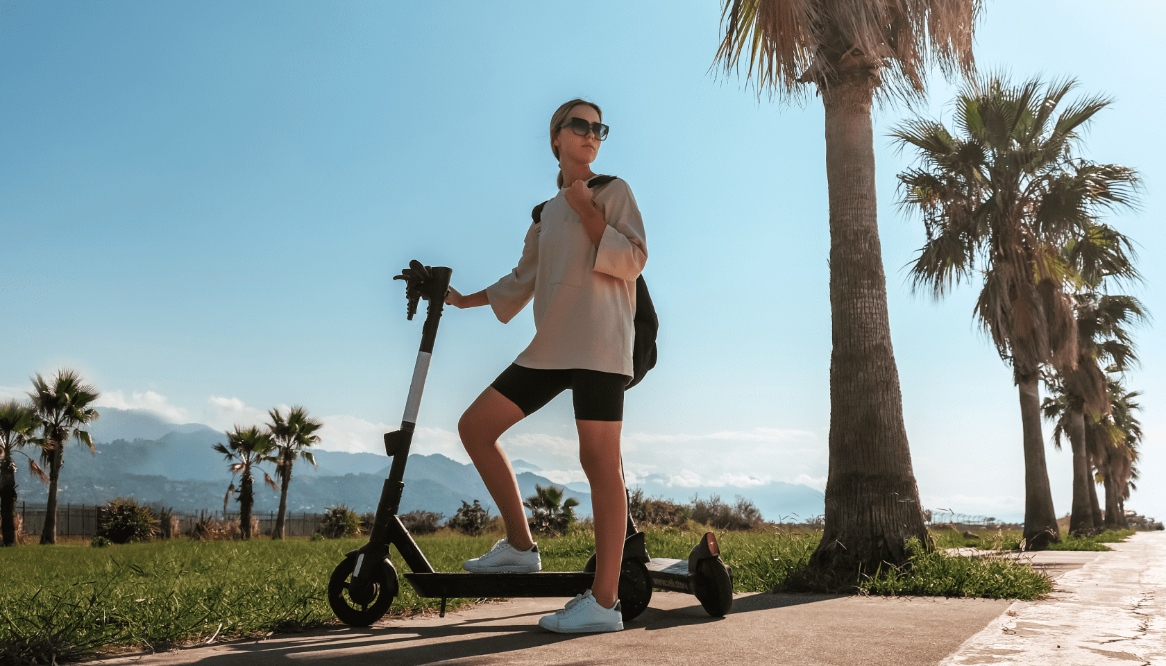 Chica joven descansa en un patinete en un paisaje natural.