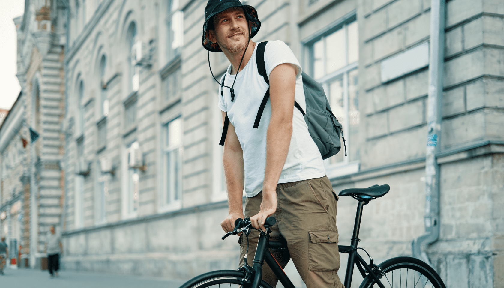 Joven sonriente está parado en una bicicleta en la calle de una ciudad.