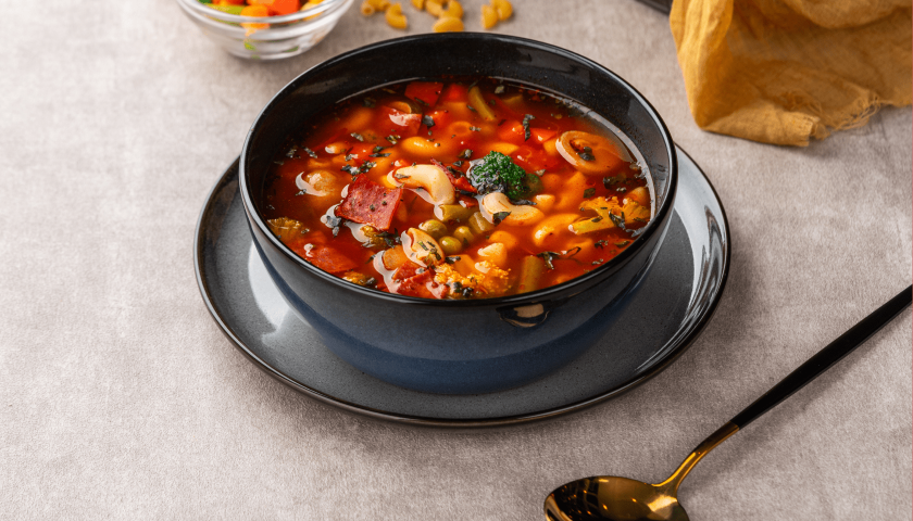 Guiso castellano con carne y verduras en un cuenco de color azul con detalles dorados.